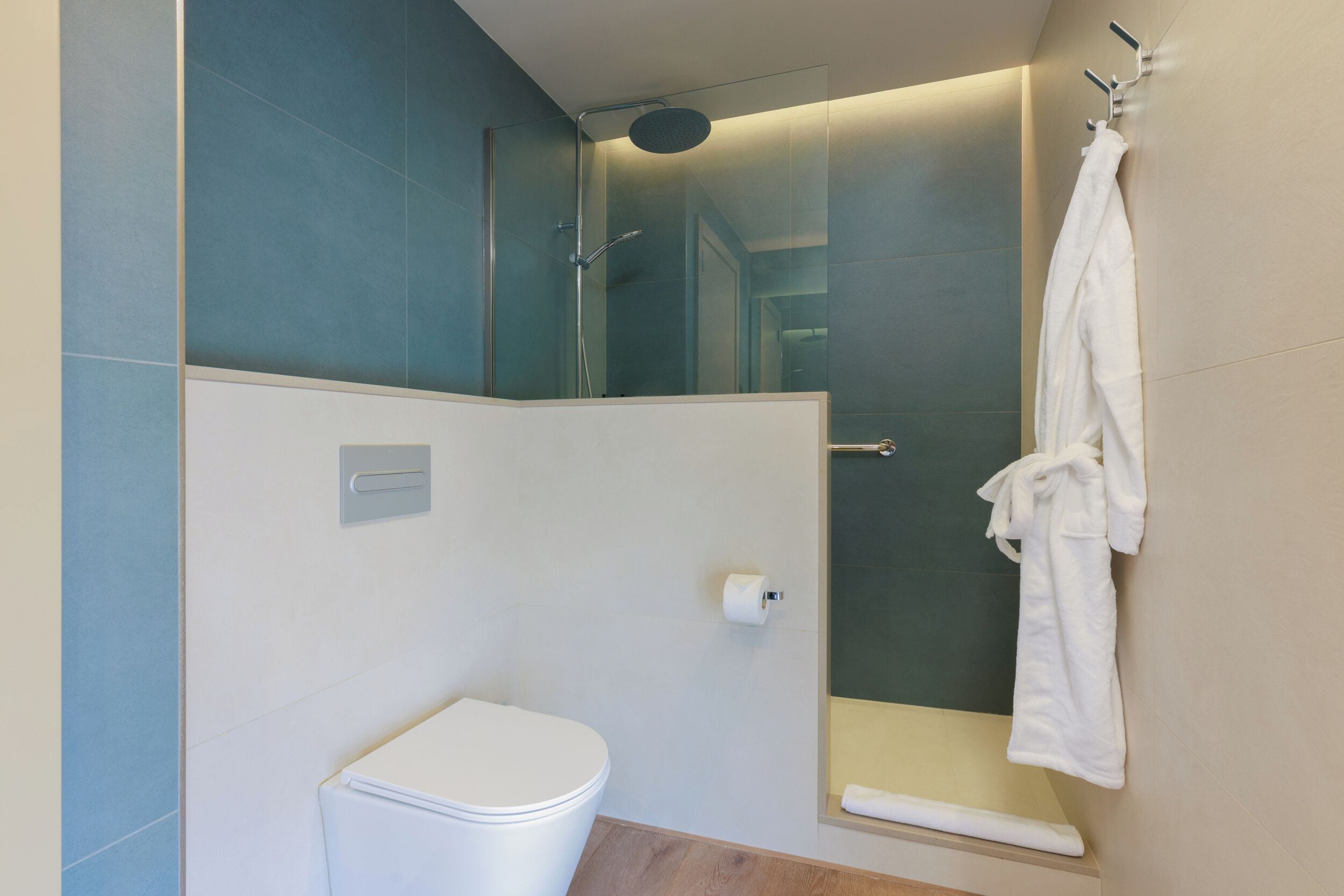 A modern bathroom with a glass-enclosed shower, a toilet, and a towel rack.