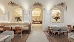 A modern restaurant with wooden tables and chairs, a central counter, and arched doorways. - Hotel Medinaceli (Barcelona)