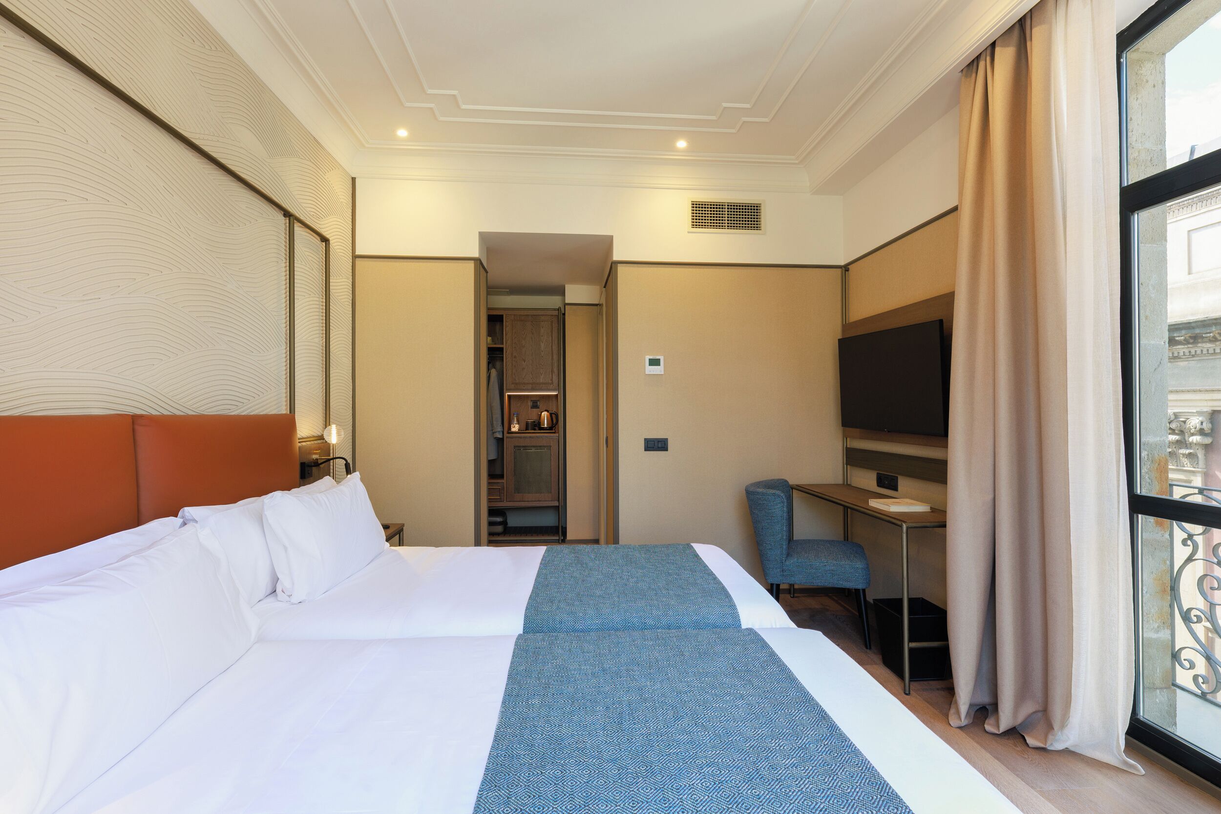 A hotel room with a large bed, a desk, a chair, and a TV.