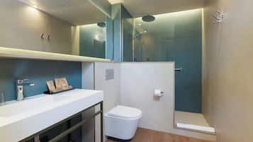Un baño moderno con un lavamanos blanco, un inodoro y una ducha con mampara de vidrio.