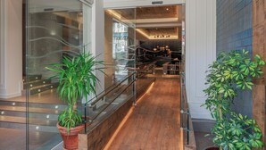 A modern interior with a wooden staircase, glass railings, and potted plants. - Hotel Medinaceli (Barcelona)