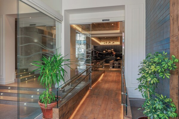 Stylish interior with a wooden floor, glass railings, and lush greenery.