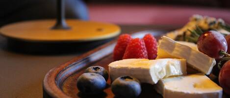 Una tabla de madera con queso, fresas y arándanos.