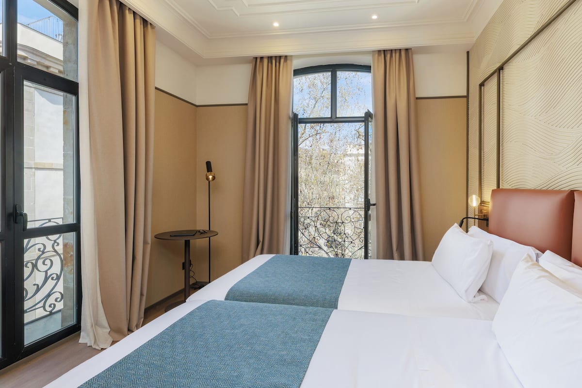 Quarto de hotel com uma cama grande, uma mesa pequena e vista para o exterior.