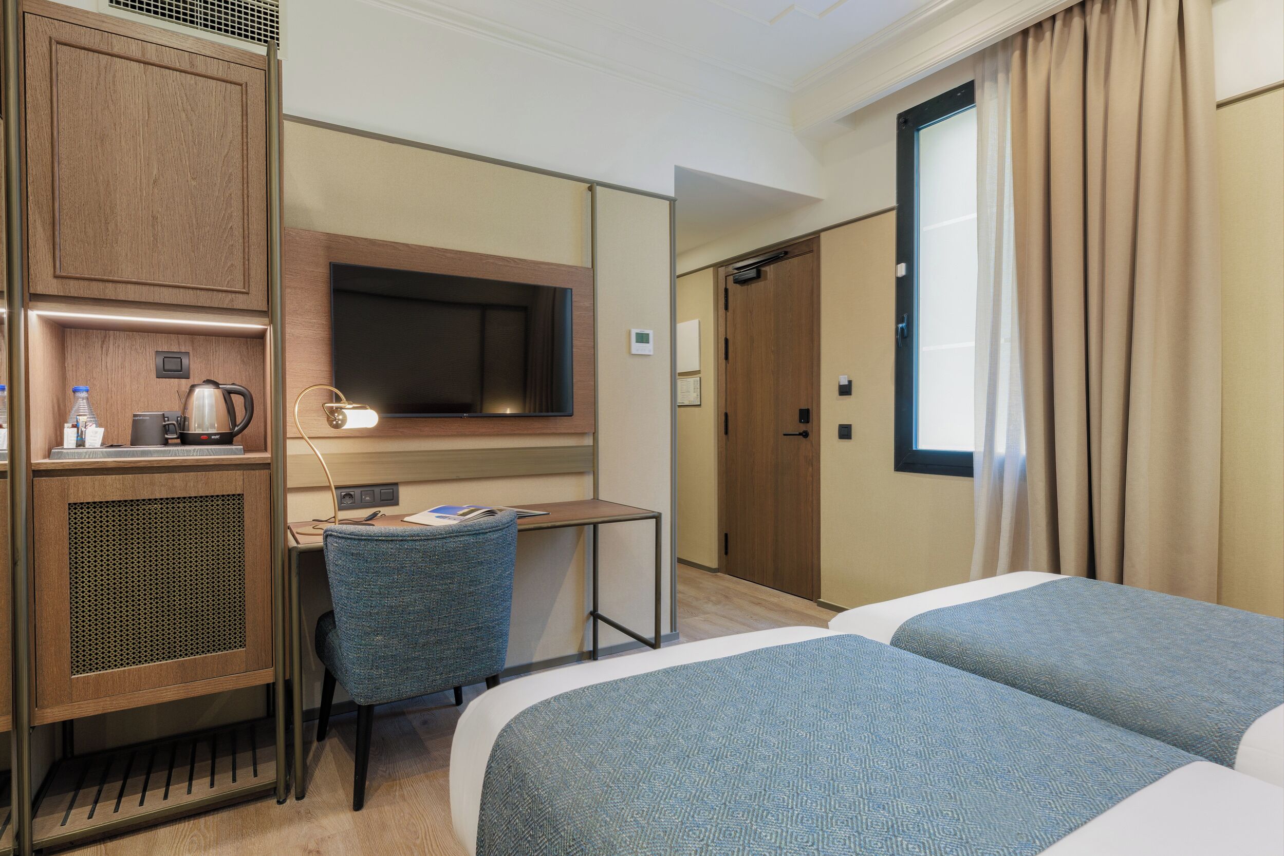 Ein Hotelzimmer mit einem Bett, einem Schreibtisch mit Stuhl, einem Fernseher und einem Kleiderschrank.