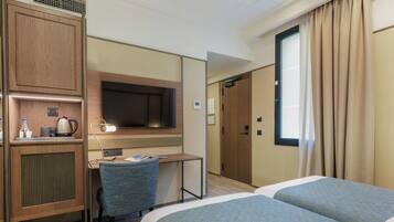 Ein Hotelzimmer mit Bett, Schreibtisch, Stuhl, Fernseher und Kleiderschrank.