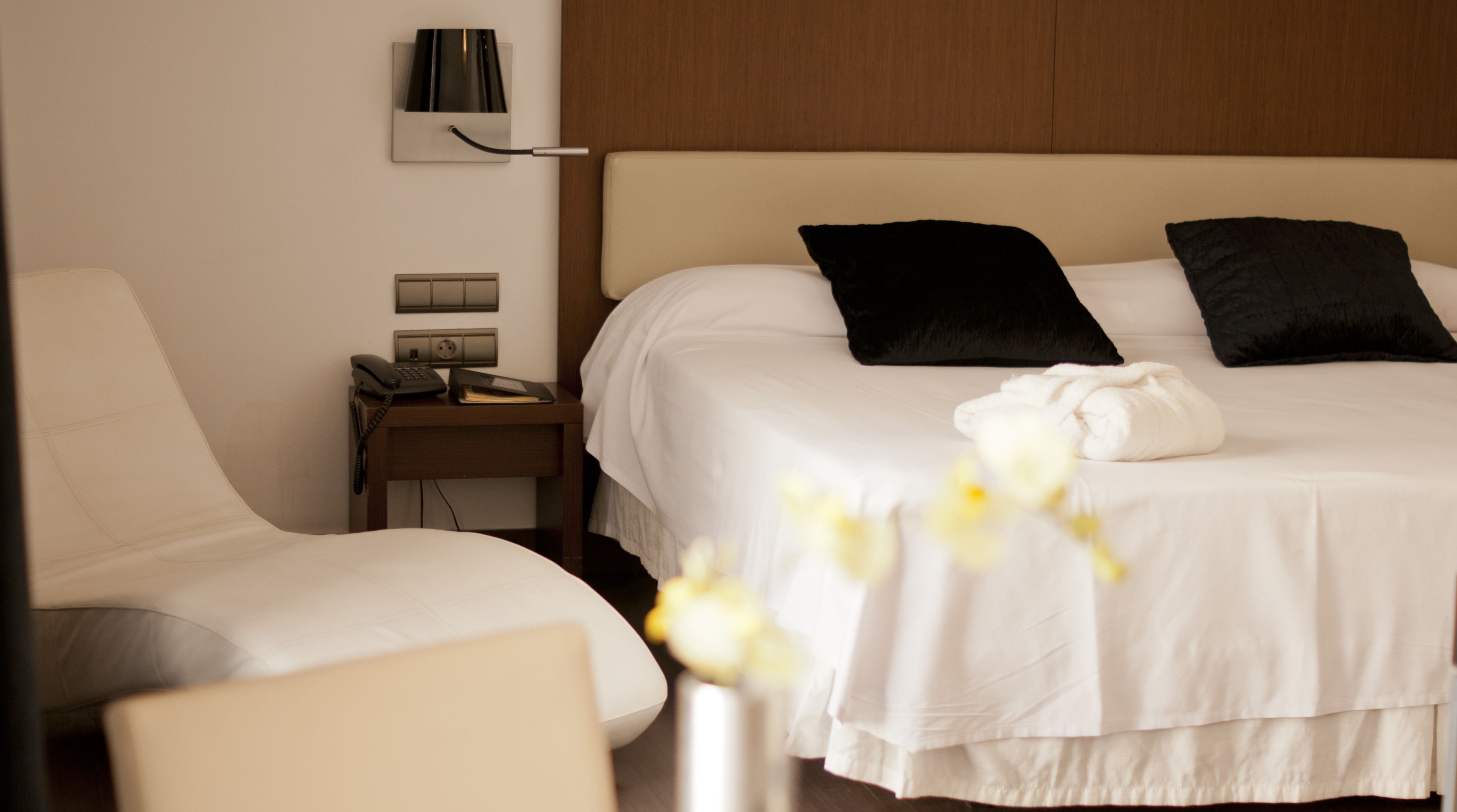 Une chambre d’hôtel comprenant un lit, une table de chevet avec une lampe, un téléphone et une chaise.