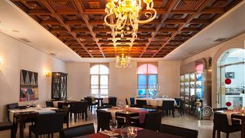 Comedor de hotel con techo de madera, candelabros y mesas dispuestas para comer.