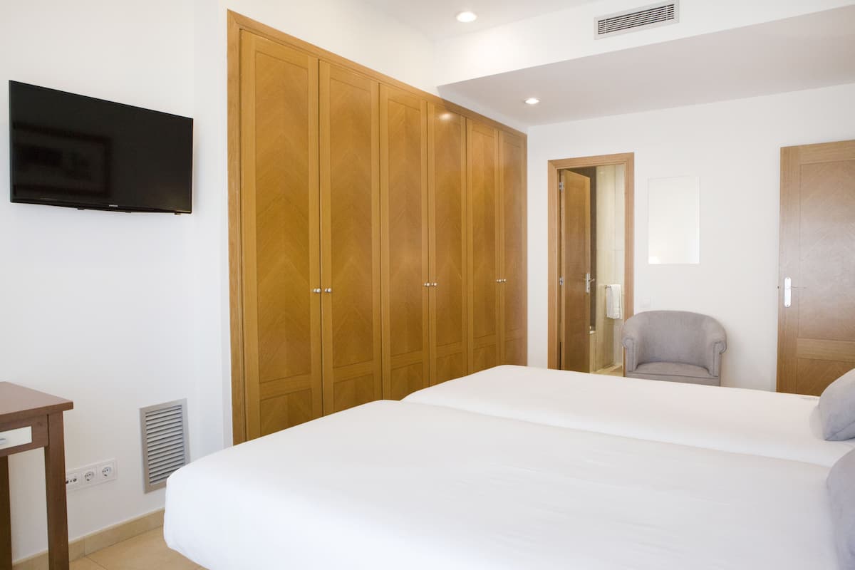 Un dormitorio con una cama grande, un armario de madera, un televisor y una silla.