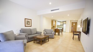 A living room with two sofas, a coffee table, and a TV on the wall. - Albufera Apartotel (Alfafar)