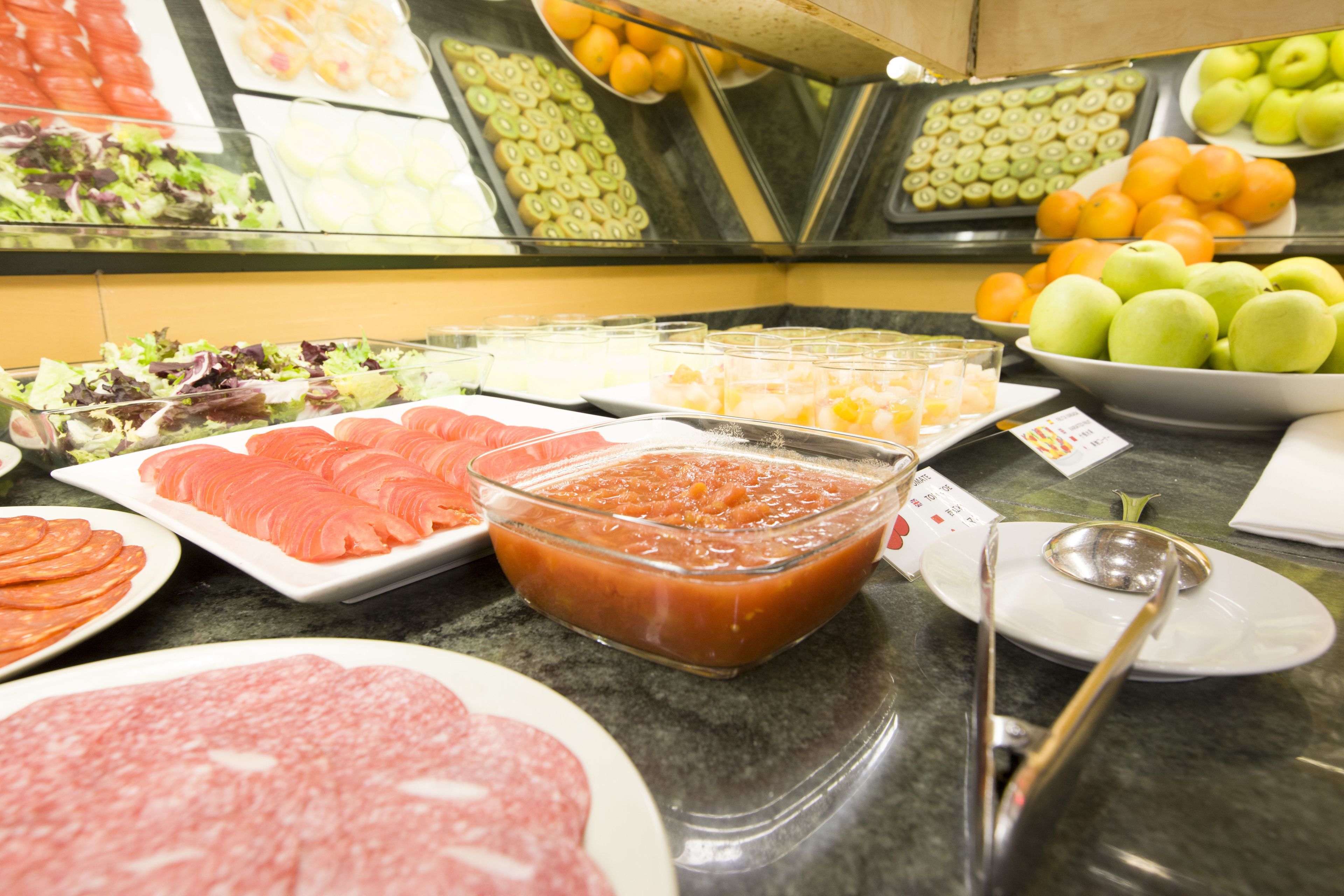 A buffet with various food items including sliced meats, salads, and fruits.