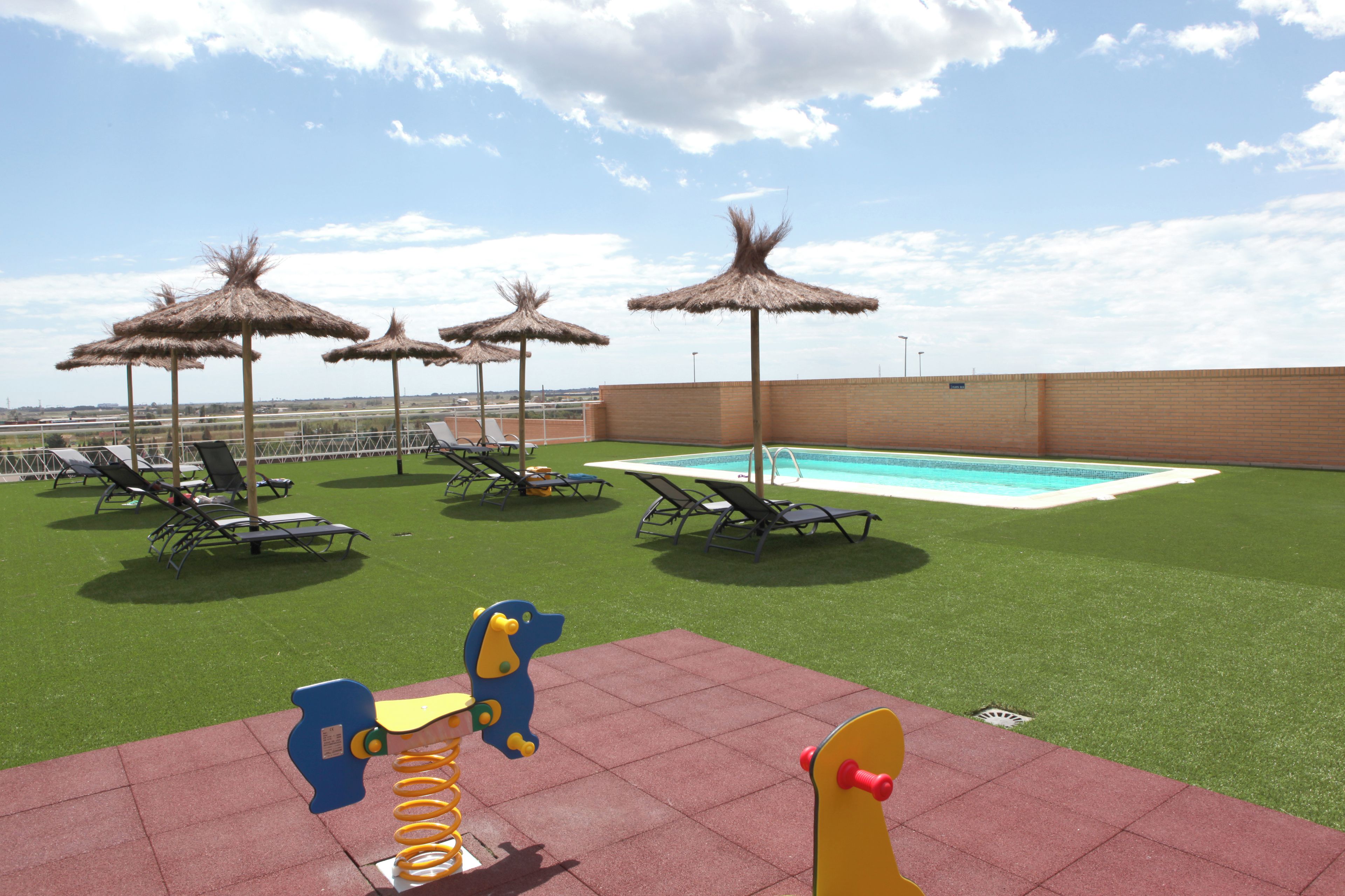Un'area piscina con lettini, ombrelloni e giochi per bambini.