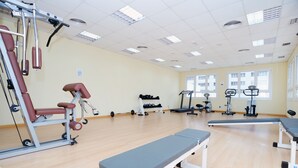 A gym with exercise equipment, benches, and a large window. - Albufera Apartotel (Alfafar)