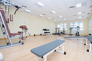 A gym with exercise equipment, benches, and a large window.