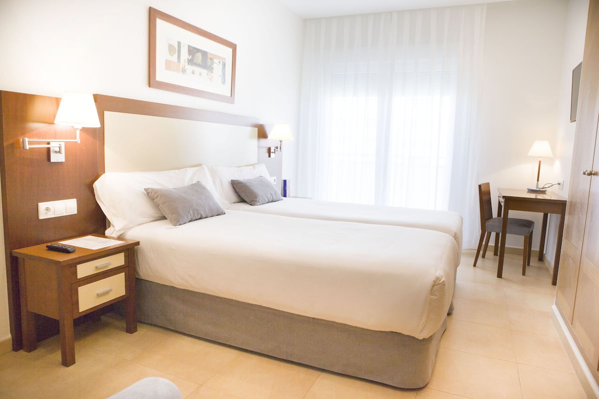 Una habitación de hotel con una cama grande, mesitas de noche, un escritorio y una silla.