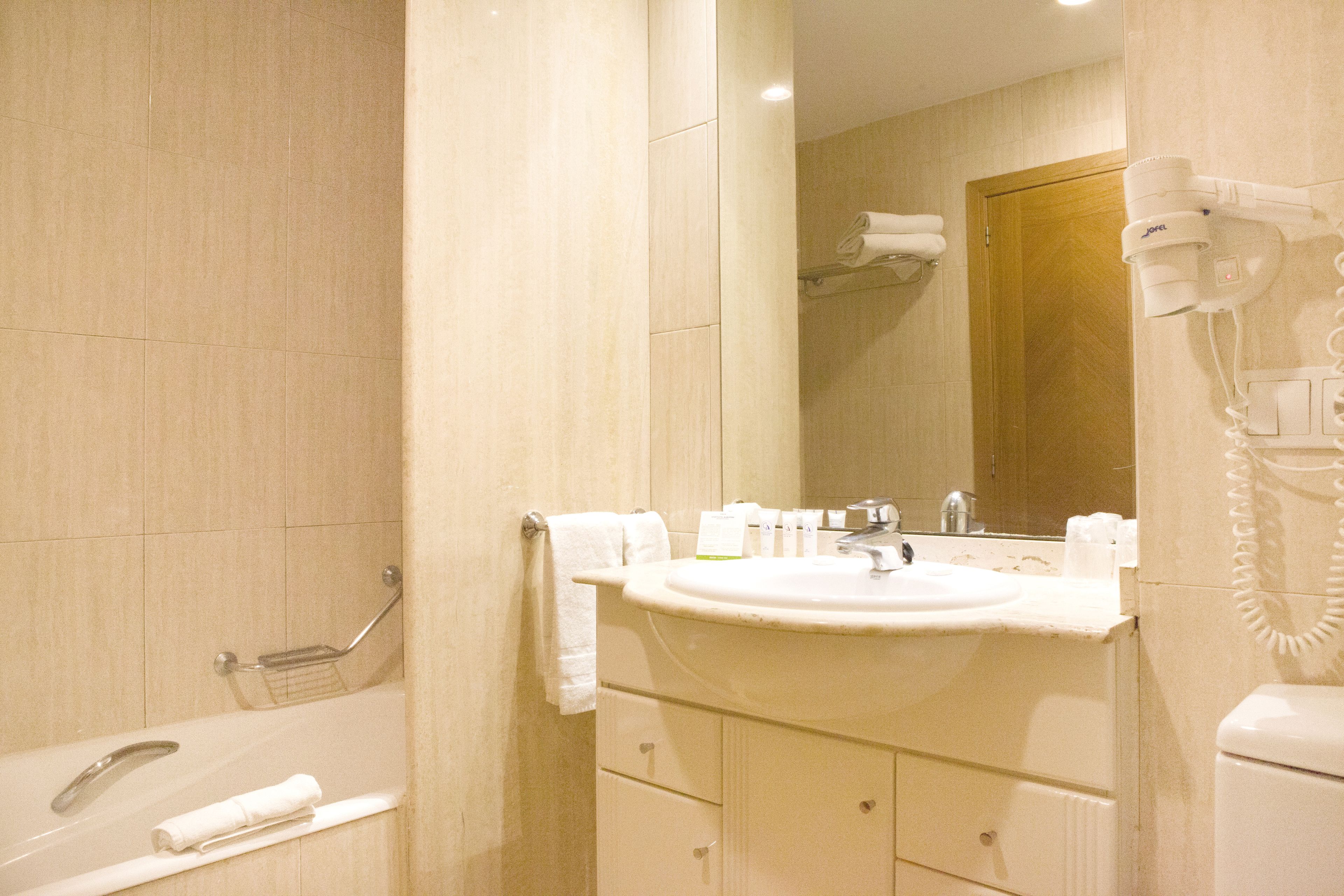 Une salle de bain équipée d’un lavabo, d’un miroir, d’un porte-serviettes et d’un sèche-cheveux.