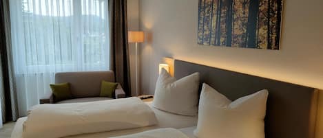 A hotel room with two beds, a sofa, a lamp, and a painting on the wall.