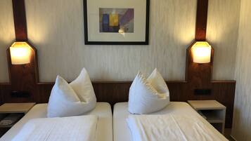 A hotel room with two beds, a framed abstract painting on the wall, and bedside lamps.