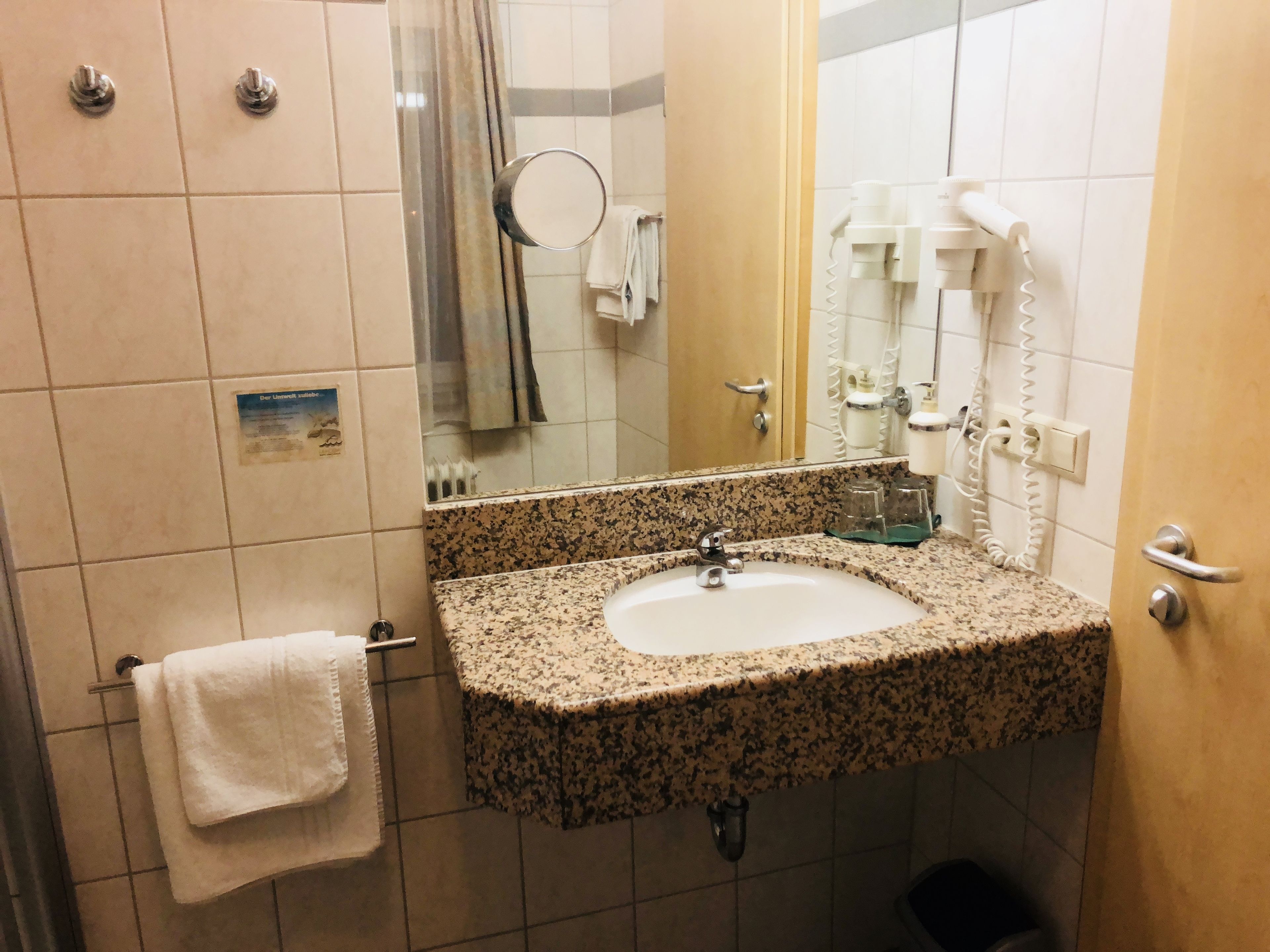 A bathroom with a granite countertop sink, a mirror, a towel rack, and a shower curtain.