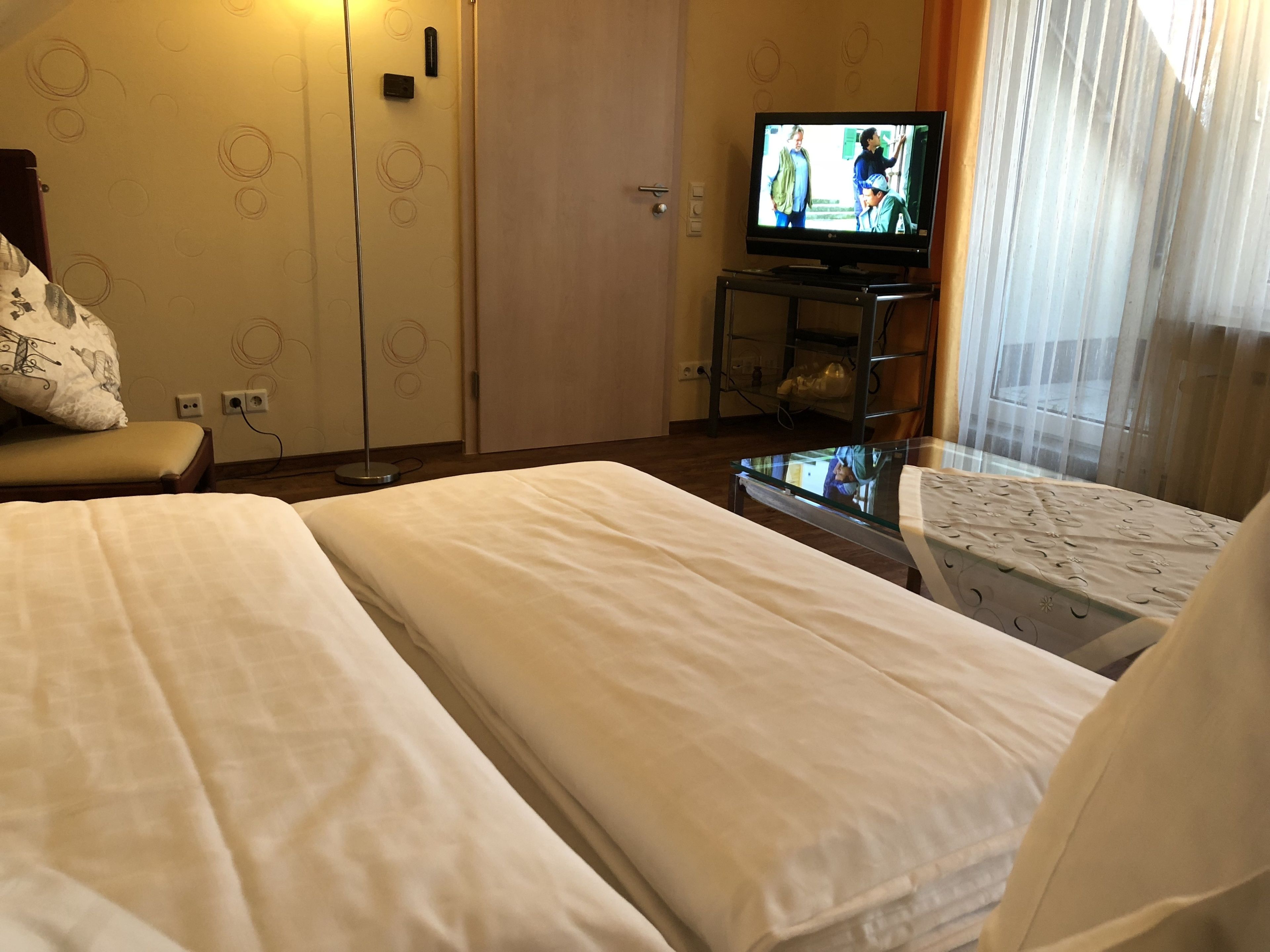 Een hotelkamer met twee bedden, een televisie op een standaard, een bureau en een stoel.
