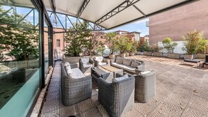 Un patio al aire libre con mobiliario de mimbre, una zona de estar techada y plantas en macetas.