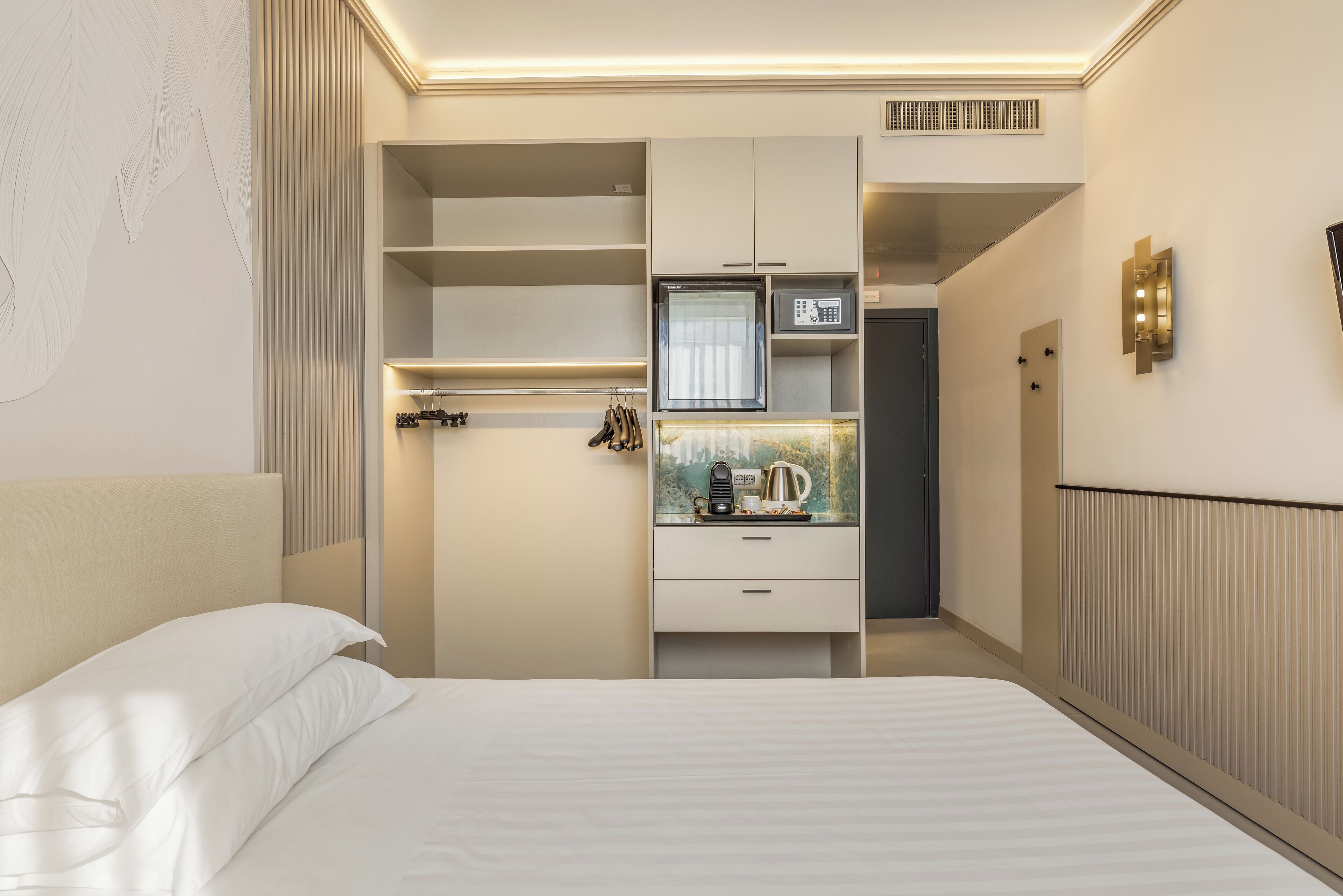 Ein modernes Schlafzimmer mit Bett, eingebautem Kleiderschrank und einer kleinen Küchenzeile.