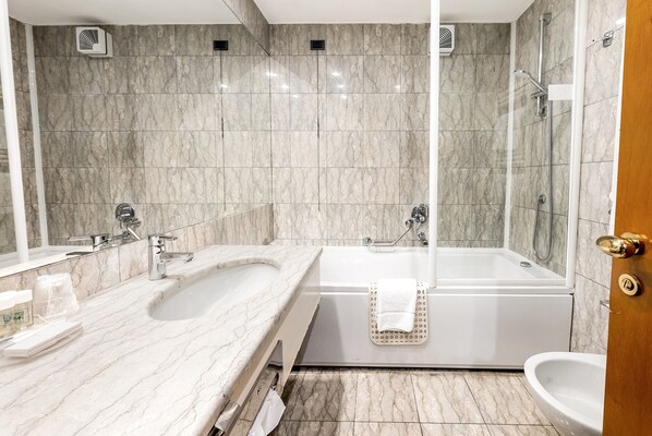 Un baño moderno con tocador de mármol, bañera y ducha.