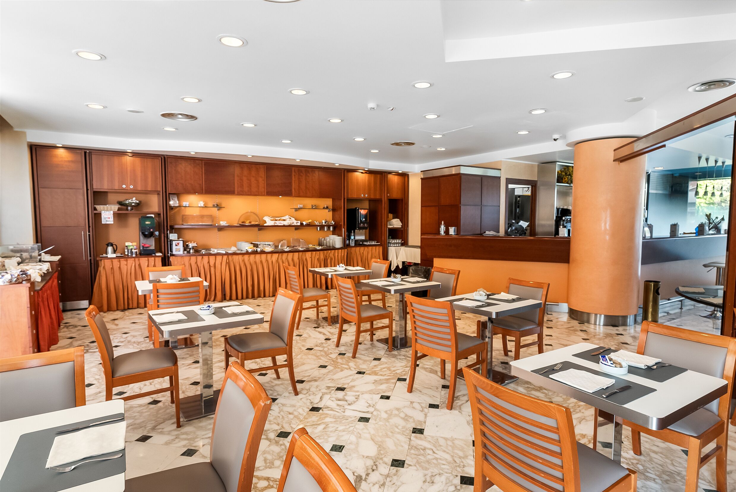 Un restaurant moderne avec des meubles en bois, un sol en marbre et un bar central.