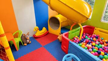 A children's play area with a slide, ball pit, and various toys.