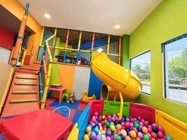 Un área de juegos infantiles con tobogán, estructuras para escalar y piscina de pelotas.
