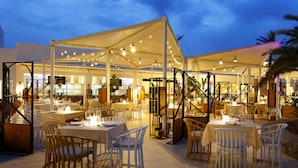 An outdoor dining area with tables and chairs, a covered seating area, and string lights.