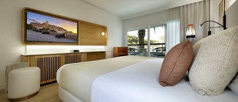 A modern hotel room with a large bed, a flat-screen TV mounted on the wall, a balcony with a view, and a wooden floor.