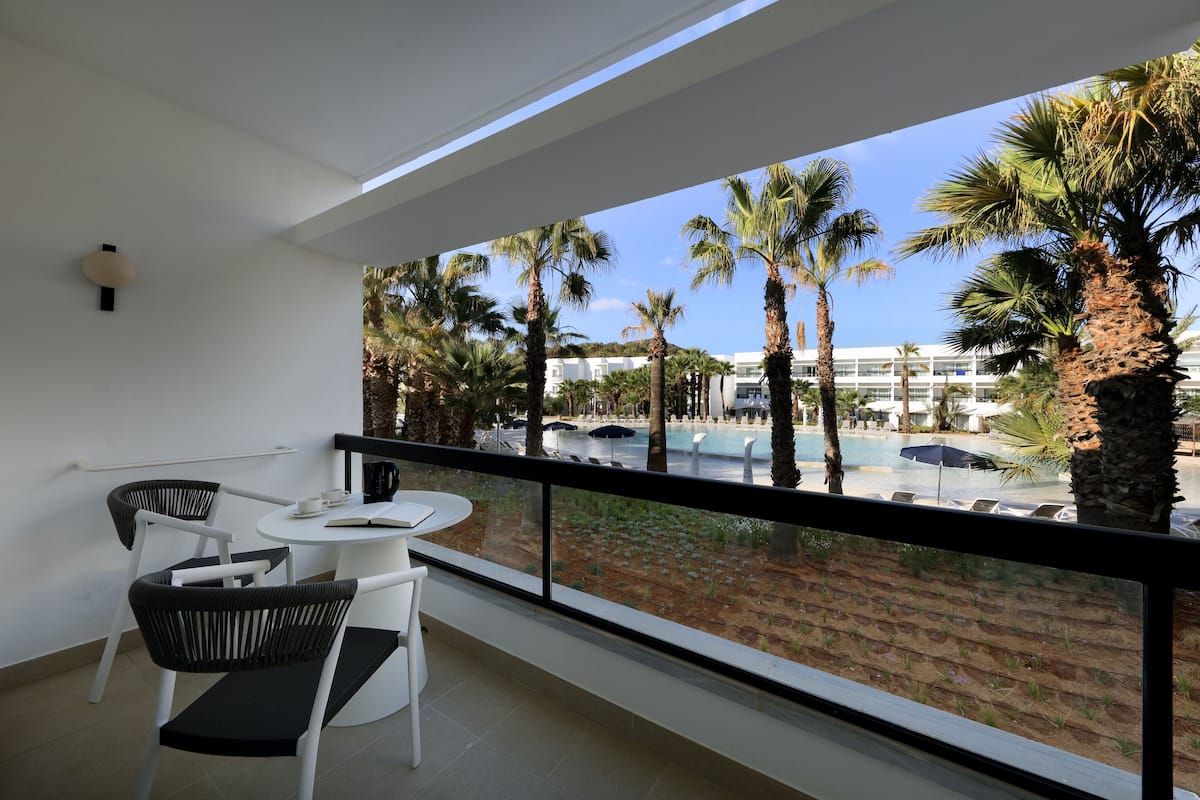 A balcony with a view of a pool and palm trees.