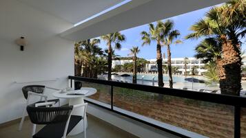 A balcony with a view of a pool and palm trees.