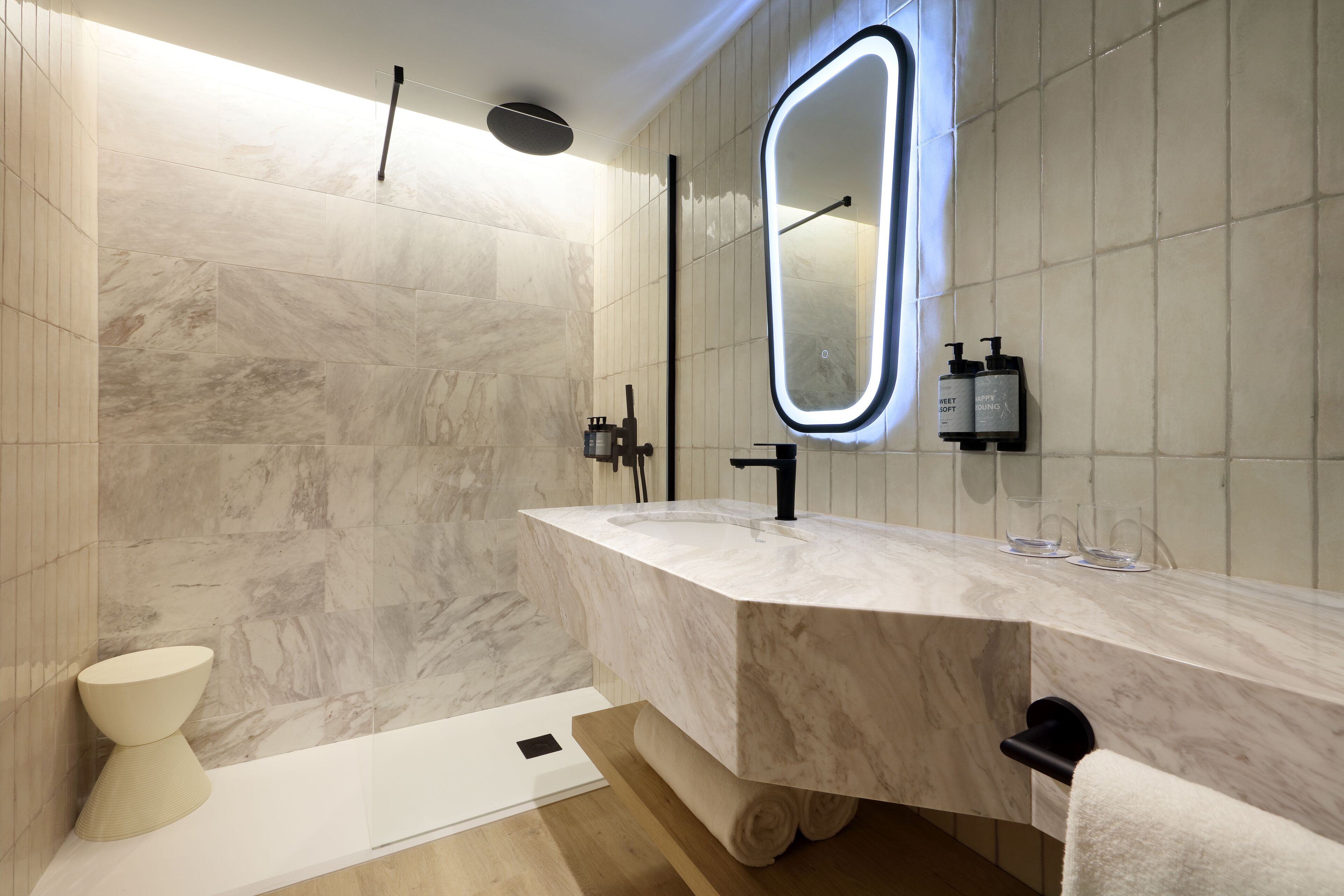 Une salle de bain moderne avec un lavabo en marbre, un grand miroir et un porte-serviettes.