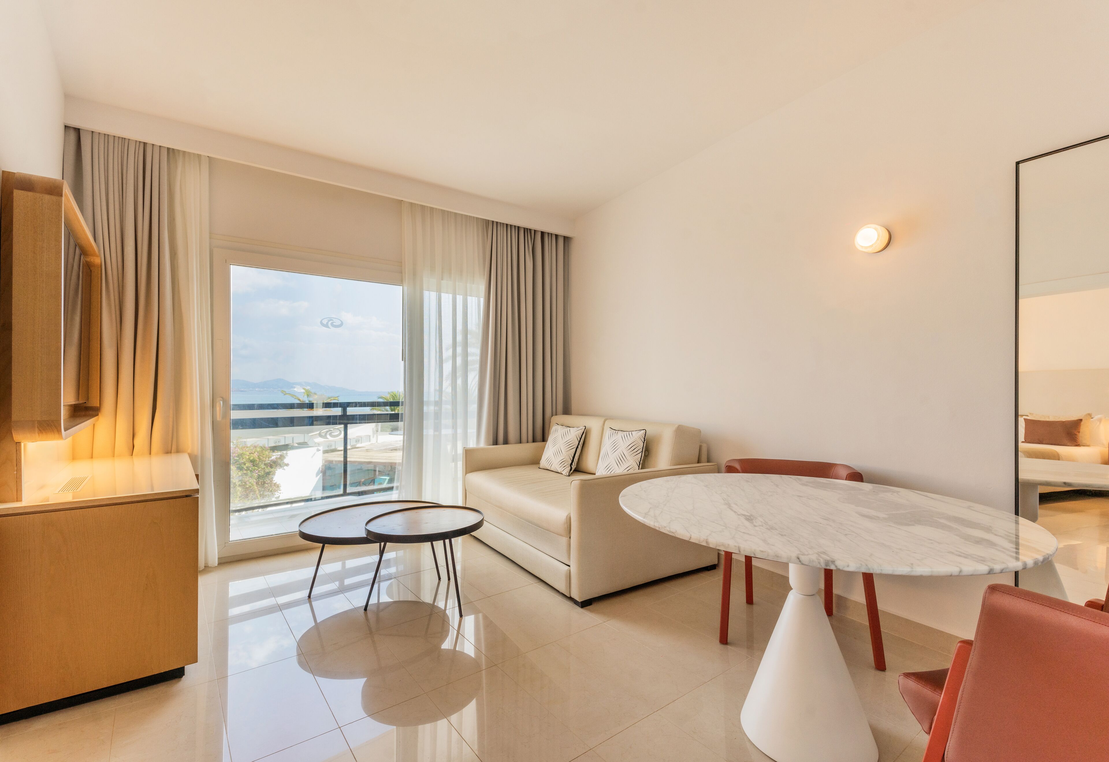 Een moderne hotelkamer met een bank, een eettafel en een keukenhoek.