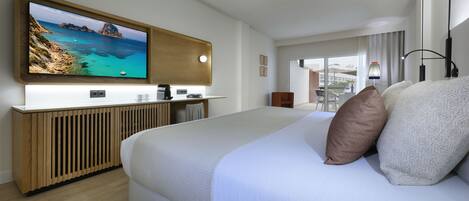 Una habitación de hotel moderna con una cama grande, un televisor montado en un mueble de madera y vistas al mar por la ventana.