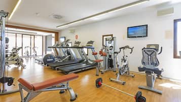 Une salle de sport équipée de tapis de course, d’appareils de musculation et d’un banc.