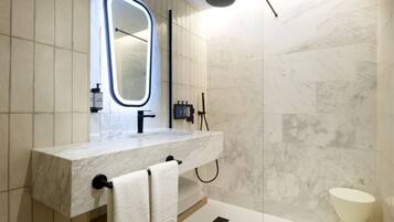 A modern bathroom with a marble sink, a large mirror, and a shower.