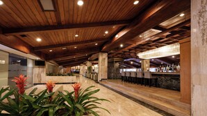 A spacious lobby with a wooden ceiling, a bar area with stools, and a reception desk.