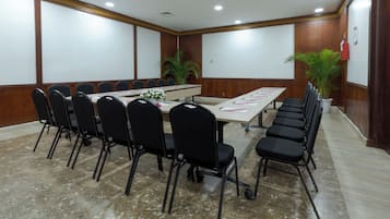 A conference room with a long table, black chairs, and a projector screen.