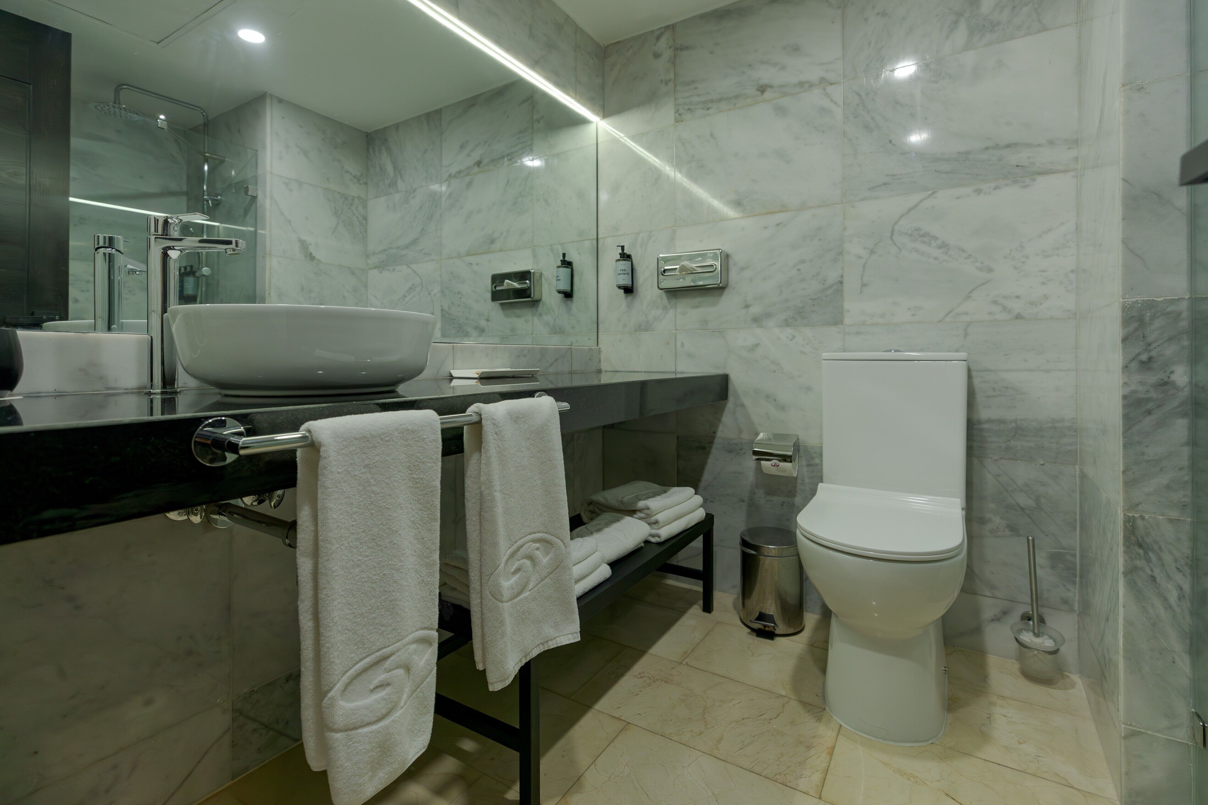 A modern bathroom with a large sink, mirror, and toilet.