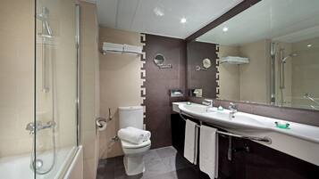 Uma casa de banho moderna com cabine de duche em vidro, sanita branca, espelho grande e lavatório com porta-toalhas.