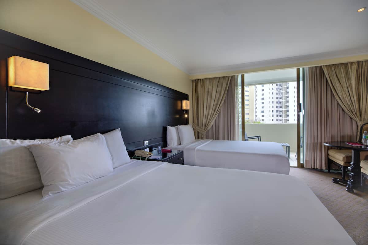 A hotel room with two beds, a desk, a chair, and a large window with curtains.