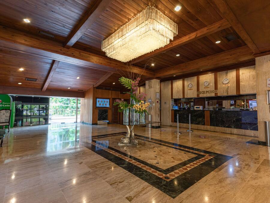 A lobby with a wooden ceiling, a chandelier, a reception desk, and a floor with a geometric pattern.