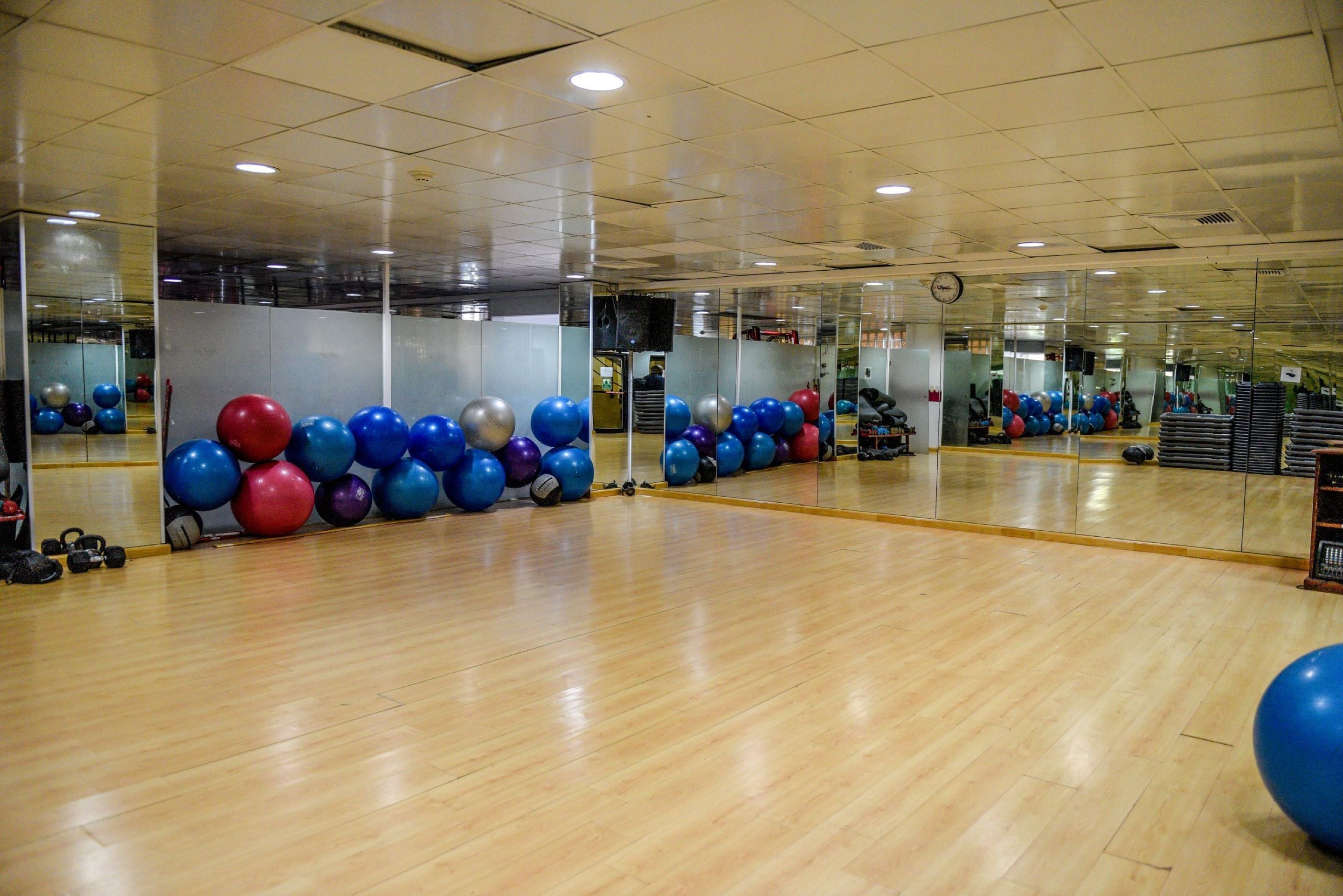 A spacious gym with wooden floors, exercise balls, and mirrors.