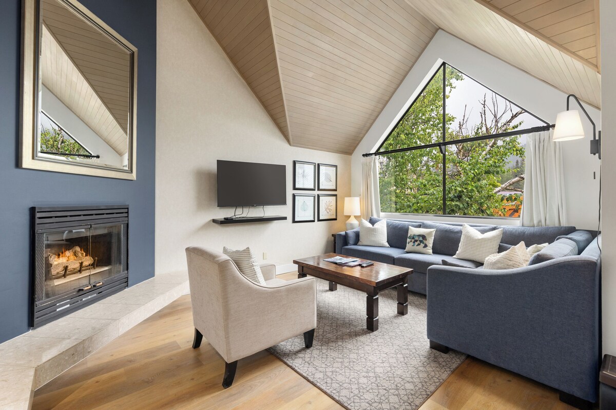 A modern living room with a fireplace, a television, a sofa, and a coffee table.