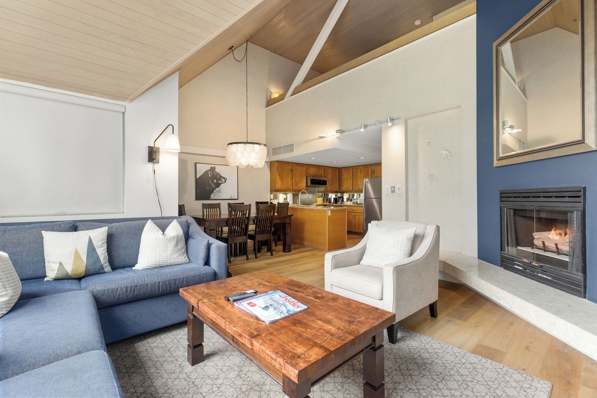 Una sala moderna con un sofá azul, una mesa de centro de madera y una chimenea.