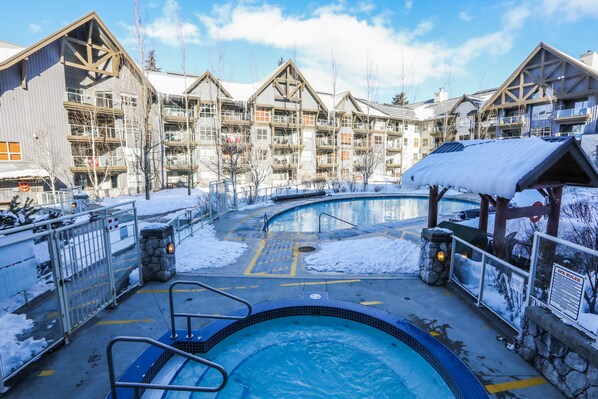 Relax by the pool with a hot tub and a small pool surrounded by the resort's multi-story buildings with balconies.