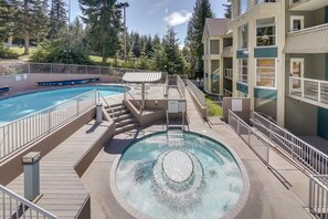 Un espace piscine doté d’un jacuzzi, d’un escalier et d’un bâtiment avec des balcons.